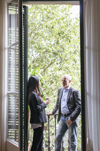 Geschäftsmann und Frau stehen auf einem Balkon und unterhalten sich, lizenzfreies Stockfoto