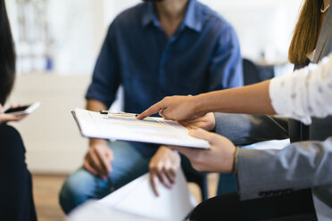 Hand pointing on chart on clipboard in a business meeting - EBSF01954