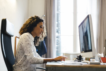 Successful businesswoman sitting in office working on computer - EBSF01958