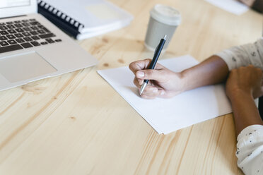 Geschäftsfrau sitzt in einer Besprechung und macht sich Notizen mit einem Kugelschreiber - EBSF01968