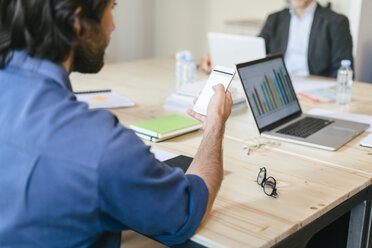 Businessman using smart phone in office meeting - EBSF01971