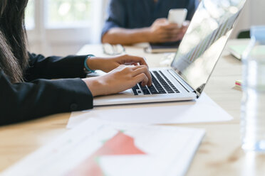 Geschäftsmann sitzt im Büro und tippt auf einem Laptop - EBSF01972