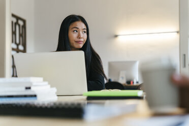 Junge asiatische Frau arbeitet im Büro mit Laptop - EBSF01974