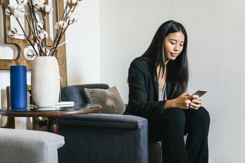 Businesswoman sitting in lounge using smart phone - EBSF01984