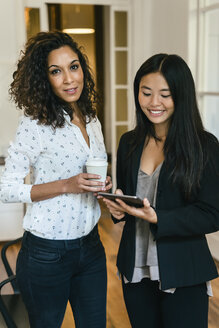 Zwei Geschäftsfrauen trinken Kaffee und benutzen ein digitales Tablet - EBSF01987