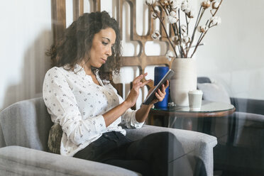 Businesswoman sitting in lounge using digital tablet - EBSF01995