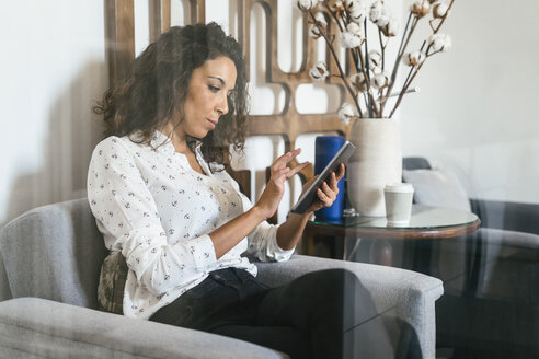 Geschäftsfrau sitzt in einer Lounge und benutzt ein digitales Tablet - EBSF01995