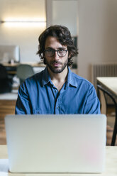 Geschäftsmann sitzt im Büro und arbeitet am Laptop - EBSF02002