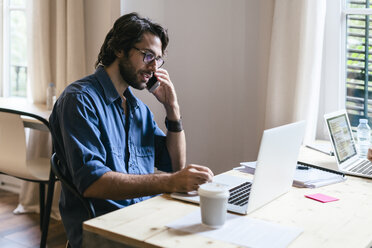 Geschäftsmann sitzt im Büro und arbeitet am Laptop - EBSF02003