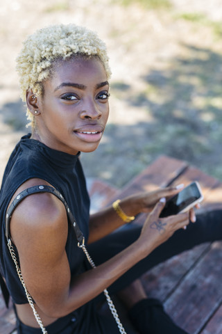 Porträt einer jungen Frau, die ein Mobiltelefon hält, lizenzfreies Stockfoto