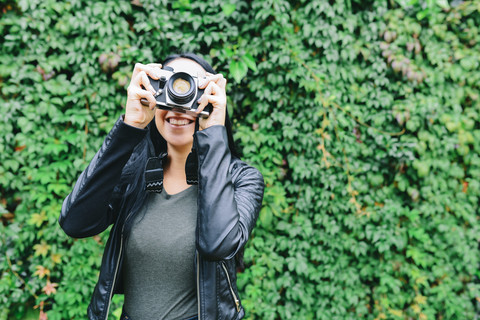 Junge Frau fotografiert mit analoger Kamera, lizenzfreies Stockfoto