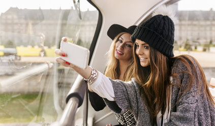France, Paris, two smiling women taking a selfie on a tour bus - MGOF02630