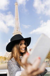 Frankreich, Paris, lächelnde Frau, die ein Selfie vor dem Eiffelturm macht - MGOF02633