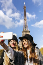 Frankreich, Paris, zwei lächelnde Frauen machen ein Selfie mit dem Eiffelturm im Hintergrund - MGOF02634