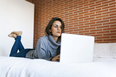 Junge Frau auf dem Bett liegend mit Laptop - VABF00853