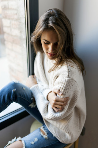 Junge Frau sitzt am Fenster, lizenzfreies Stockfoto