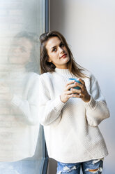 Junge Frau trinkt einen Kaffee am Fenster - VABF00868