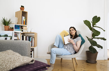 Woman at home sitting on chair looking up - FKF02075