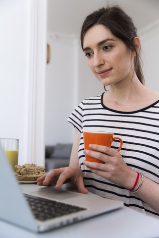 Lächelnde Frau zu Hause am Laptop, lizenzfreies Stockfoto