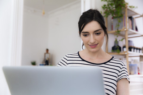 Smiling woman at home using laptop stock photo