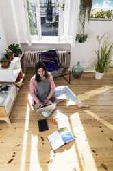 Frau zu Hause auf dem Boden sitzend mit Laptop - FKF02094