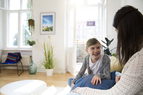 Glückliche Mutter mit Tochter zu Hause auf der Couch sitzend - FKF02103