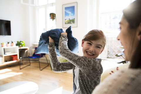 Glückliche Mutter mit Tochter zu Hause bei einer Kissenschlacht, lizenzfreies Stockfoto