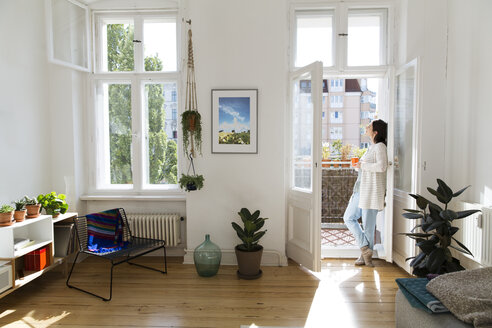 Woman at home standing at balcony door - FKF02113