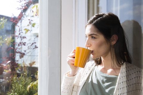 Woman drinking coffee at the window stock photo