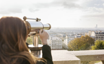 Frankreich, Paris, Montmartre, junge Frau schaut durch ein Teleskop - MGOF02651