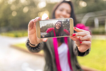 Young woman taking a selfie in a park in autumn - MGOF02653