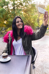 Young woman taking a selfie in a park in autumn - MGOF02657