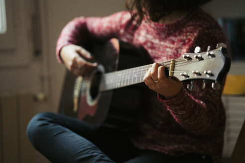 Junge Frau spielt Gitarre zu Hause - KKAF00156