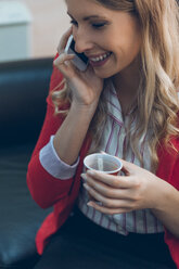 Lächelnde Frau mit Kaffee zum Mitnehmen, die mit ihrem Handy telefoniert - ZEDF00444