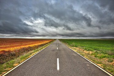 Spain, Province of Zamora, empty road and fields under cloudy sky - DSGF01198