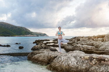 Schwangere Frau übt Yoga am Meer - DIGF01456