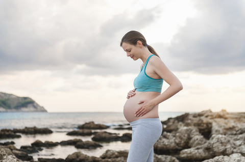 Schwangere Frau am Meer stehend, lizenzfreies Stockfoto
