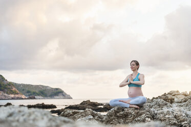 Pregnant woman practising yoga at the sea - DIGF01466