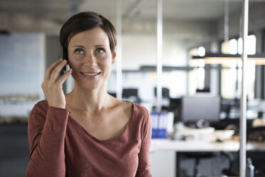 Lächelnde Geschäftsfrau im Büro am Mobiltelefon - RBF05247