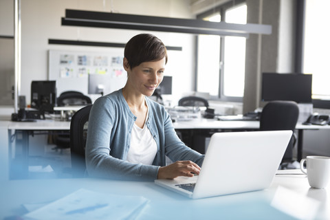 Geschäftsfrau im Büro mit Laptop, lizenzfreies Stockfoto