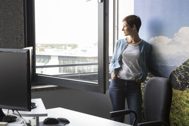 Geschäftsfrau im Büro schaut aus dem Fenster - RBF05271