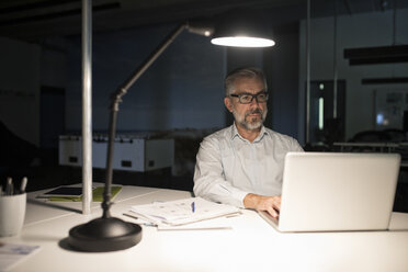 Geschäftsmann im Büro mit Laptop in der Dunkelheit - RBF05278