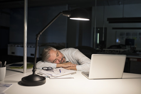 Exhausted businessman sleeping on office desk stock photo