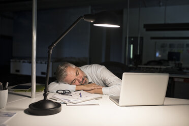 Erschöpfter Geschäftsmann schläft auf dem Bürotisch - RBF05280