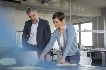 Businessman and businesswoman using laptop in office - RBF05287