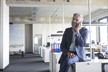 Businessman in office talking on cell phone - RBF05296