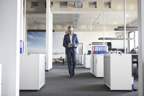 Geschäftsmann geht im Büro und hält Dokumente, lizenzfreies Stockfoto