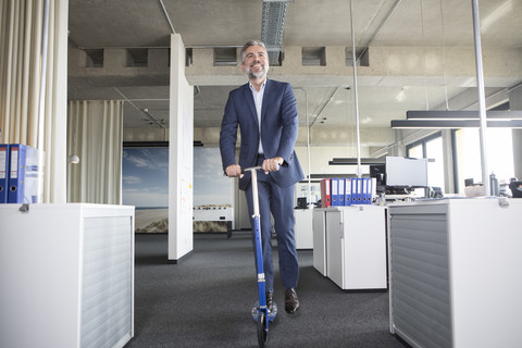 Businessman on scooter in office stock photo