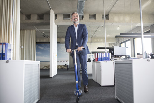 Businessman on scooter in office - RBF05302