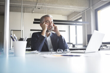 Businessman at desk in office with closed eyes - RBF05306